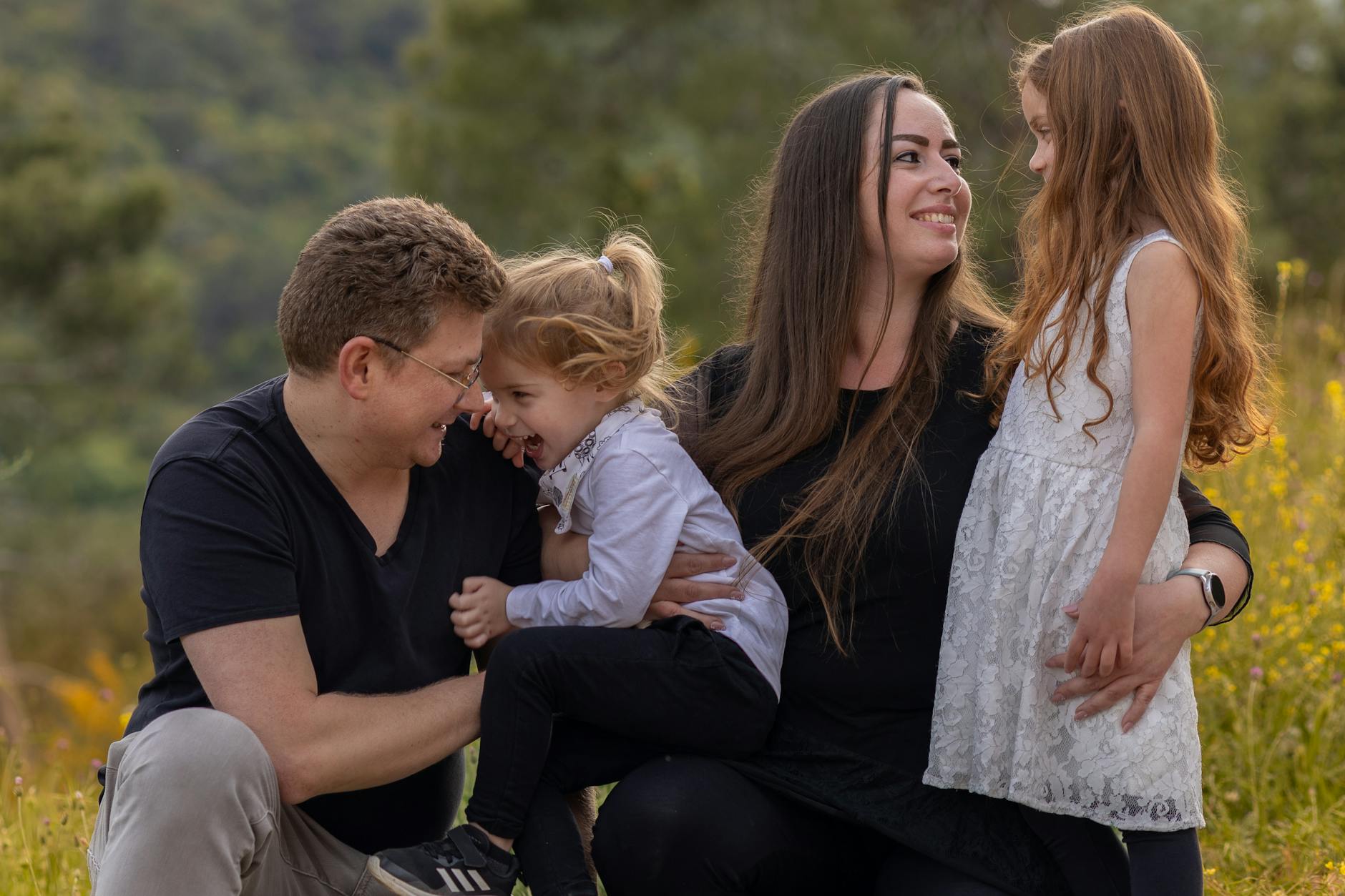 Rodzice bawią się na dworze z dwiema córkami
