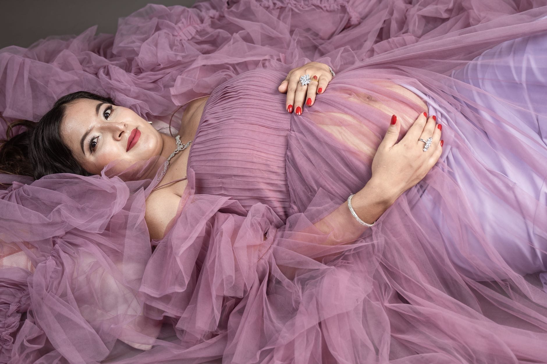 Elegancki portret ciężarnej kobiety w fioletowej sukni w studio