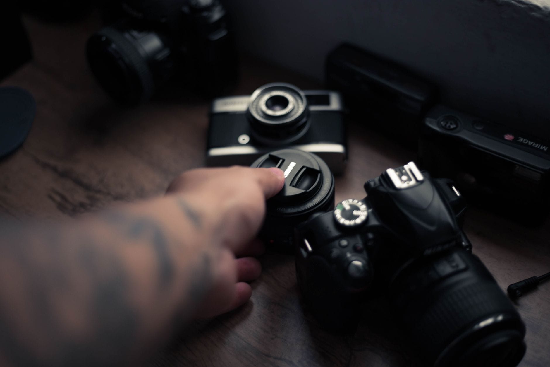 Dłoń trzymająca obiektyw nad stołem z akcesoriami fotograficznymi